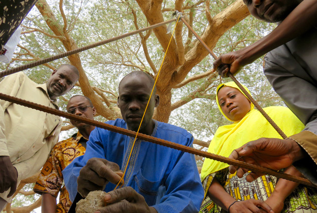 group of people constructing a tool from rebar and string